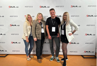 Skupina účastníků před fotostěnou s logy Sklik.cz a hashtagem SEF2023 na Seznam Fóru